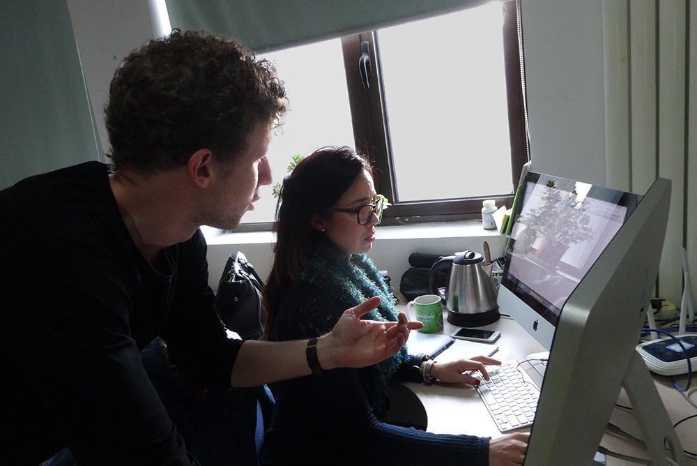 Edward talking to a colleague who is sitting at a computer