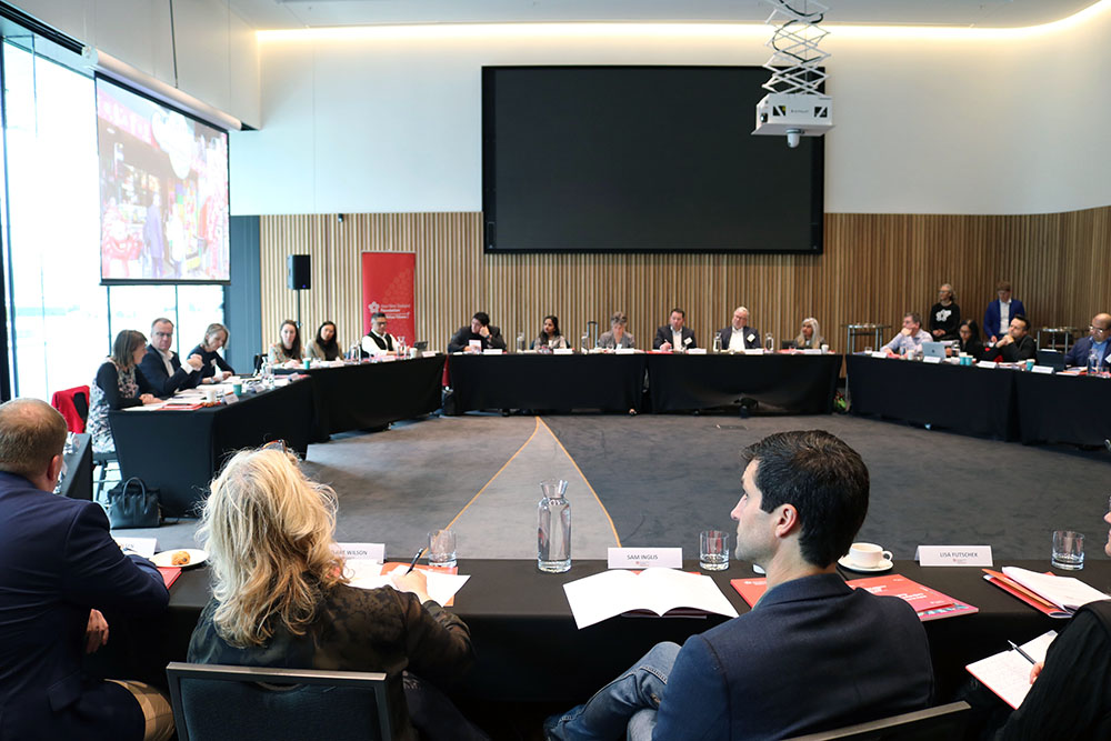 A conference room with people sitting at tables in a large circle