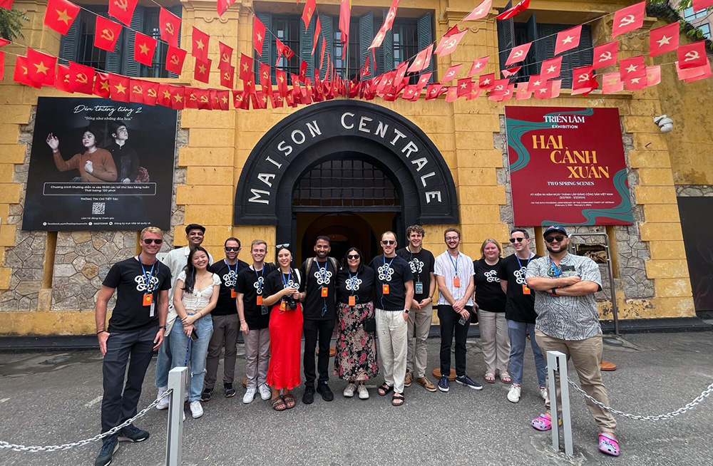A group photo of Leadership Network members standing in front of an old building with small Vietnam flag on strings above them
