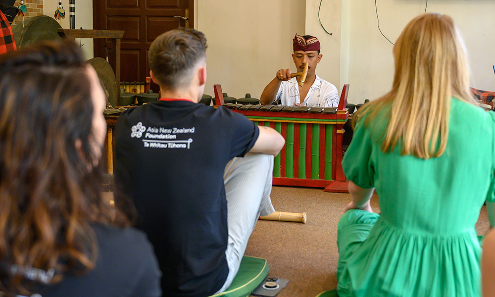 Health and beauty entrepreneurs sitting on the ground listening to a man play gamelan music
