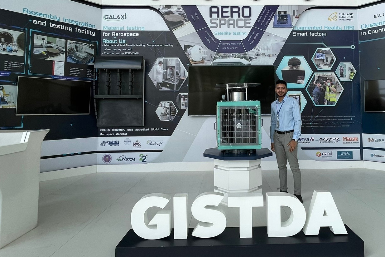 Siveshearn Jaynessh standing in front of a GSTDA sign with a wall of Aero Space diagrams behind him