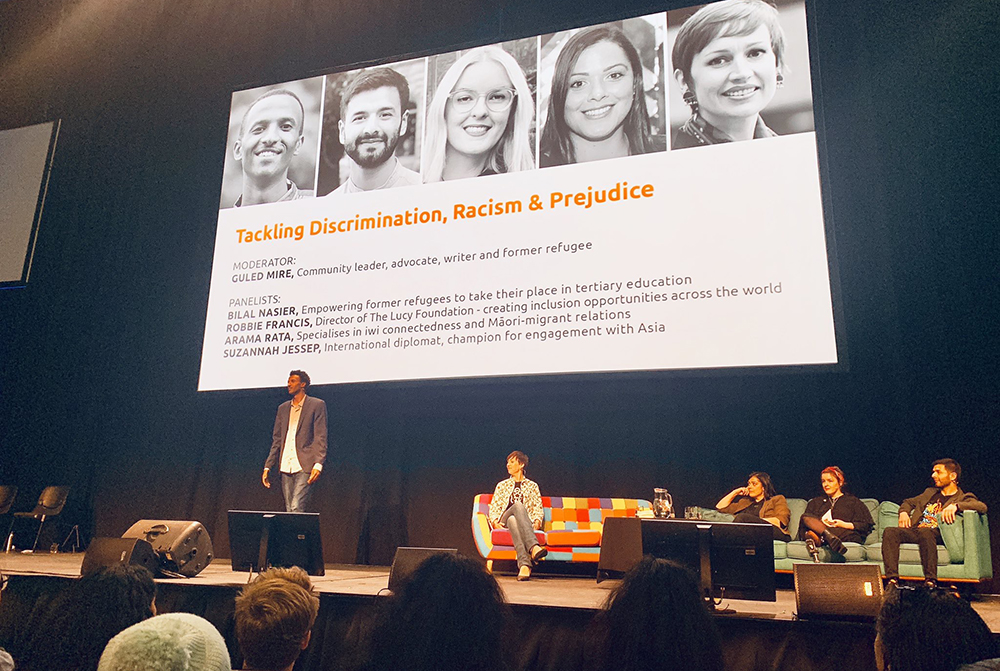 Guled Mire on a stage addressing an audience about tackling discrimination, racism and prejudice