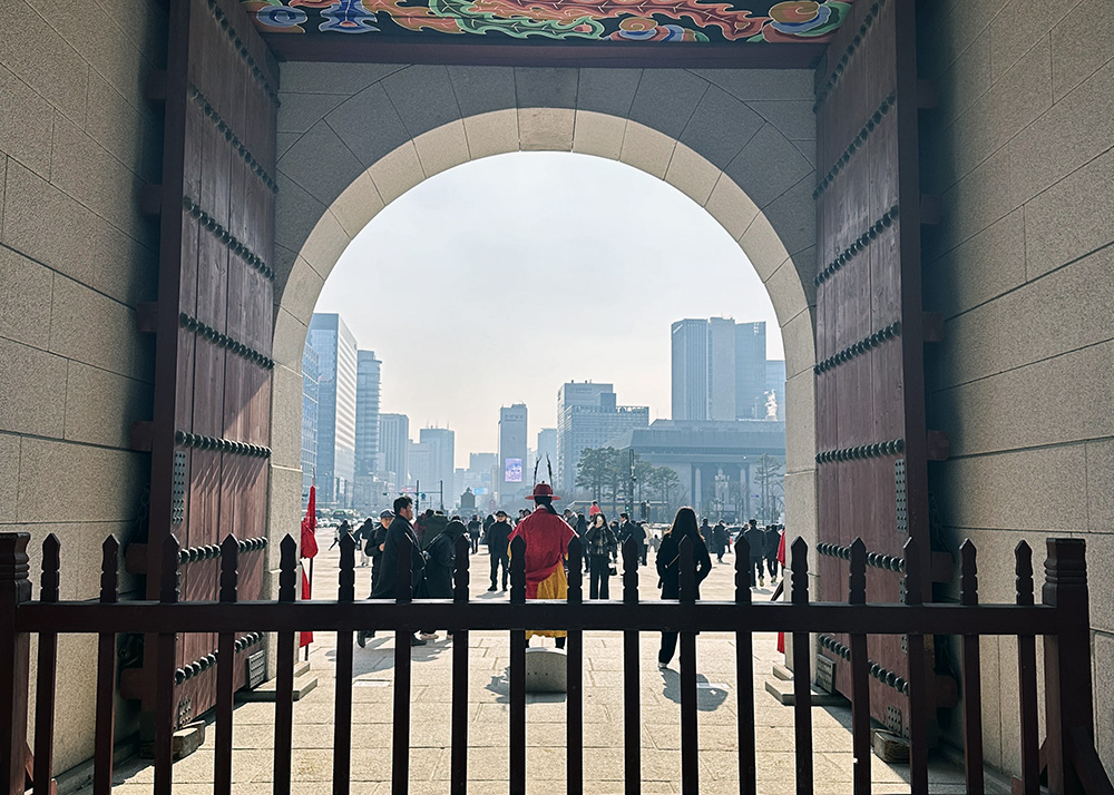 A photo looking through an archway gate across a square full of people