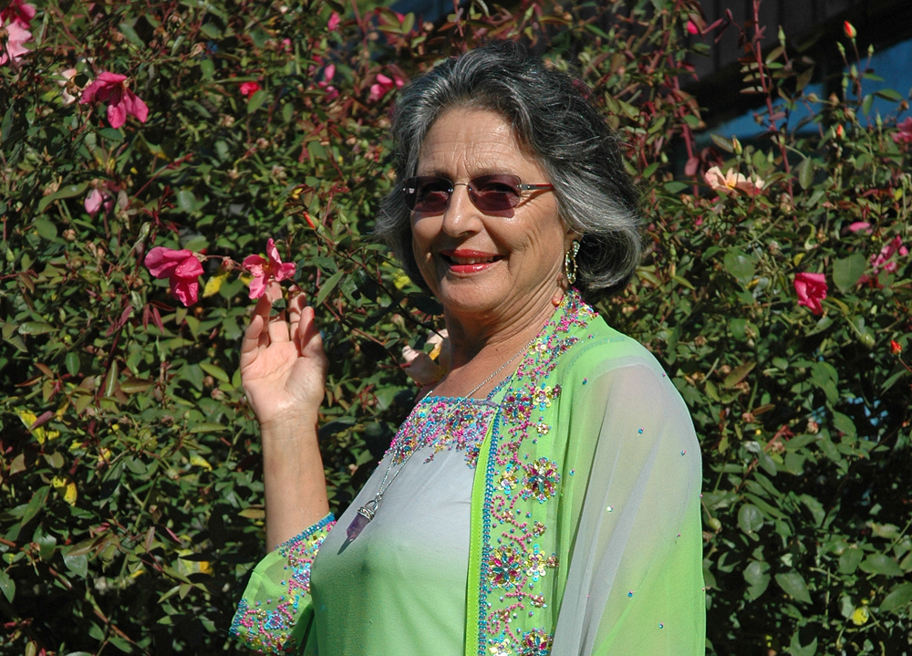 Woman standing in front of a hedge feeling the flowers