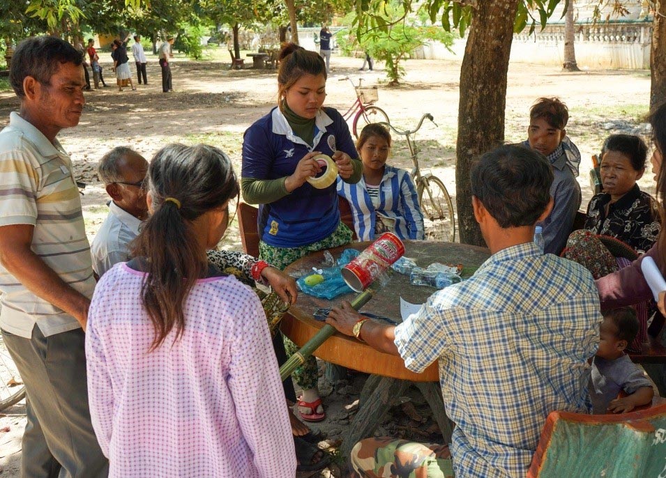 A group of people standing around working together on a contraption