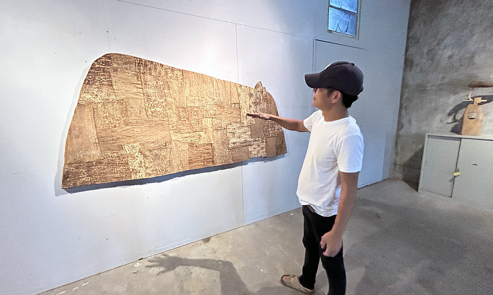 A man in a studio looking at an artwork on a wall
