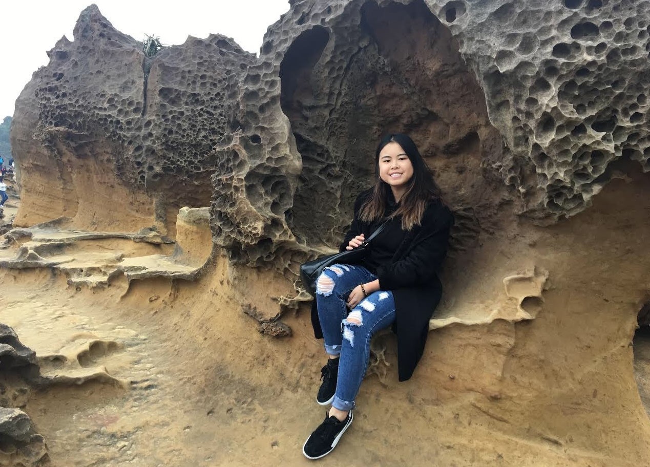 Girl sits in the curve of a rock