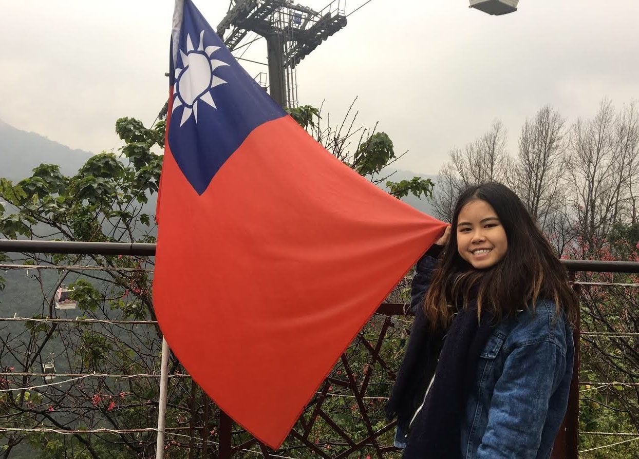 Girl stands in front of flag