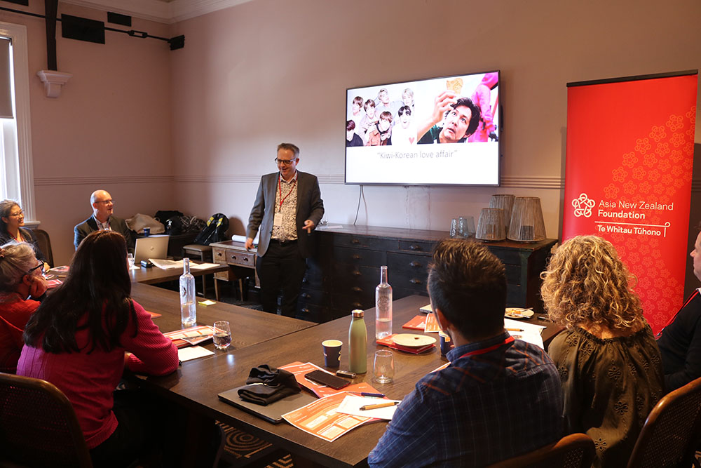 Dr Andrew Butcher talking to the teachers in front of a projector screen with an image from Squid Games on it
