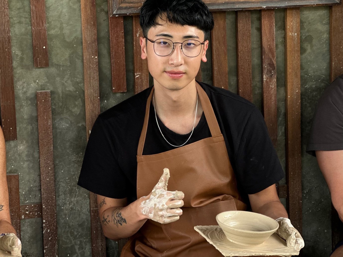 Thomas sitting at a potters wheel giving a thumbs up
