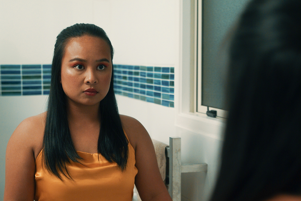 A woman in a golden dress looking at herself in a mirror
