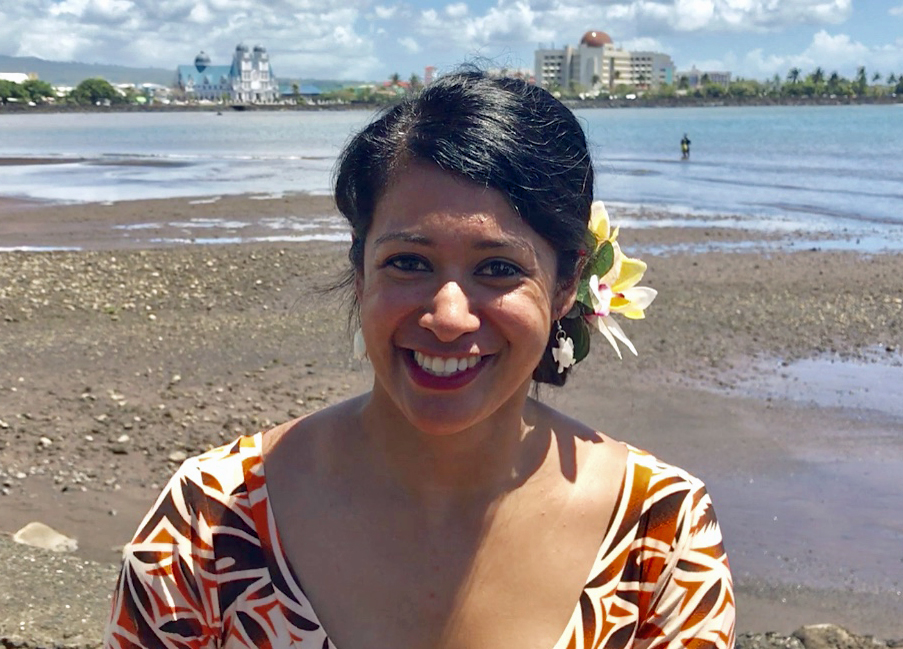 woman with flower behind ear in front of beach scene