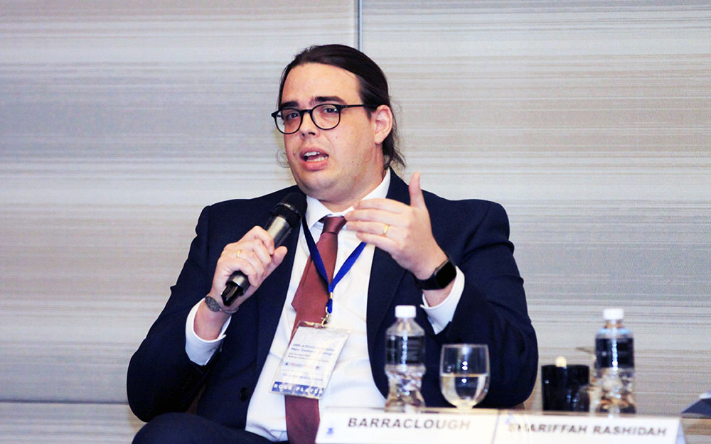 Tom Barraclough sitting at a table speaking into a microphone