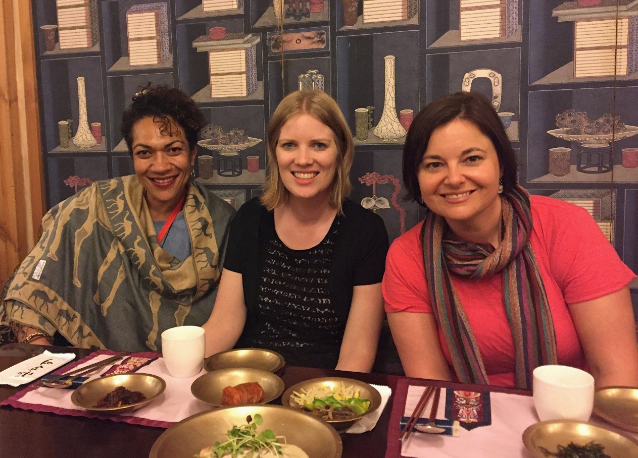 three women sitting at a dinner table with food in front of them
