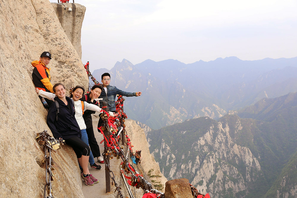 Leadership Network member Jamie on a rockface path with four friends, with a view of mountains behind them
