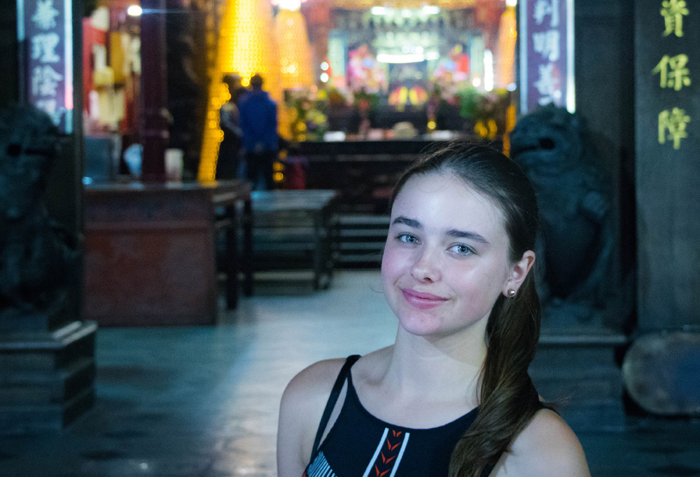 Girl standing in front of night street scene in alleyway