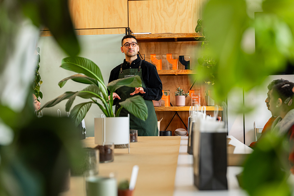 Joshua standing in front of a classroom of students with plants on their desks