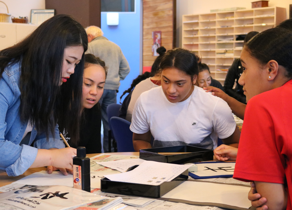 Four student working hard at a desk with caligraphy