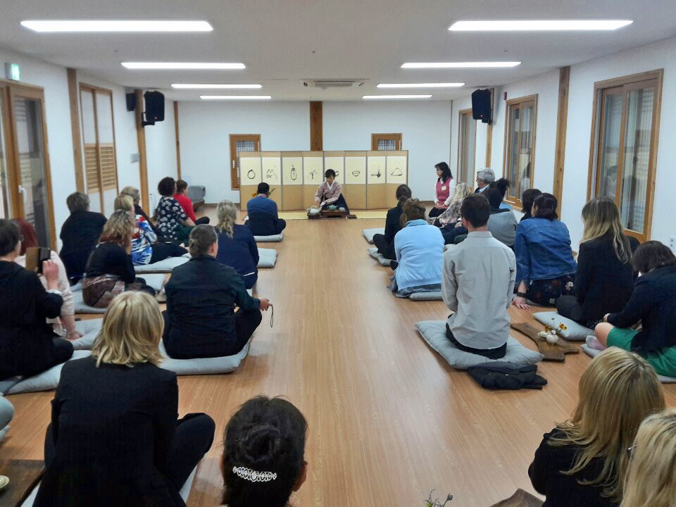 A room of adults sitting on mats looking at person at front of the room