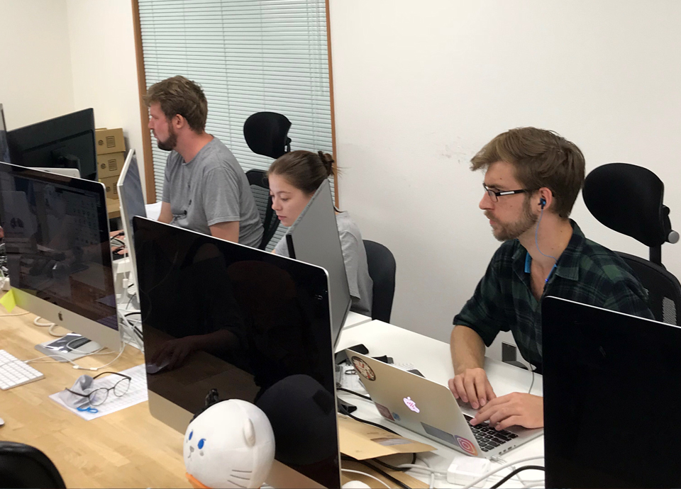 Junaye intern sitting with co workers at desk at shuttlerock