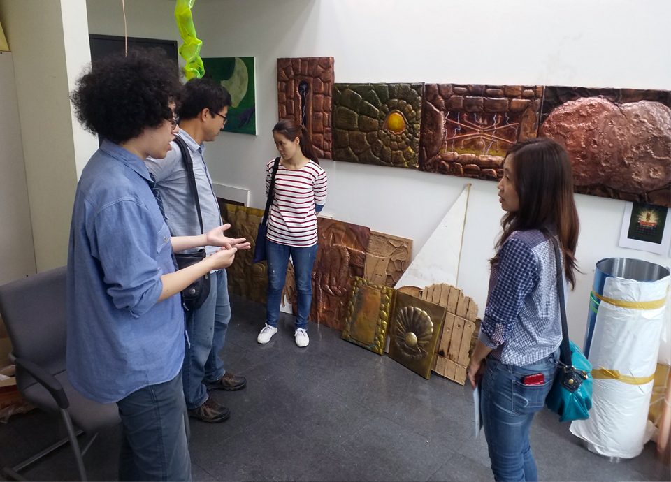 Four people standing in an arts studio talking