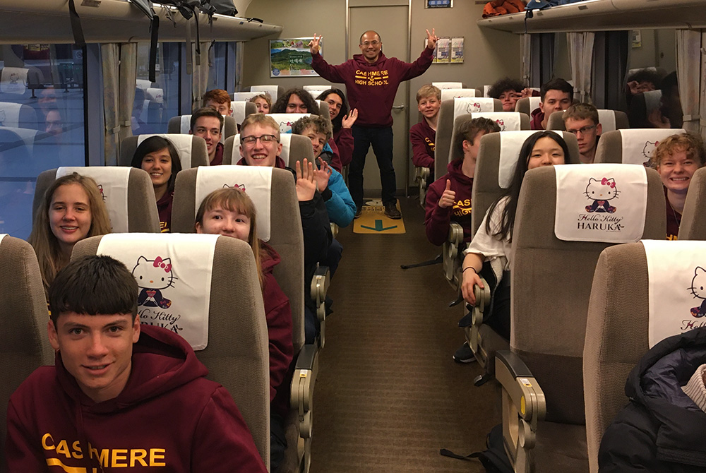 The students citing in a train carriage that has Hello Kitty headrest covers