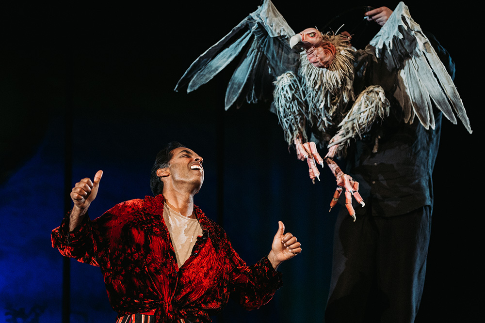 Actor Jacob Rajan on stage with a vulture puppet
