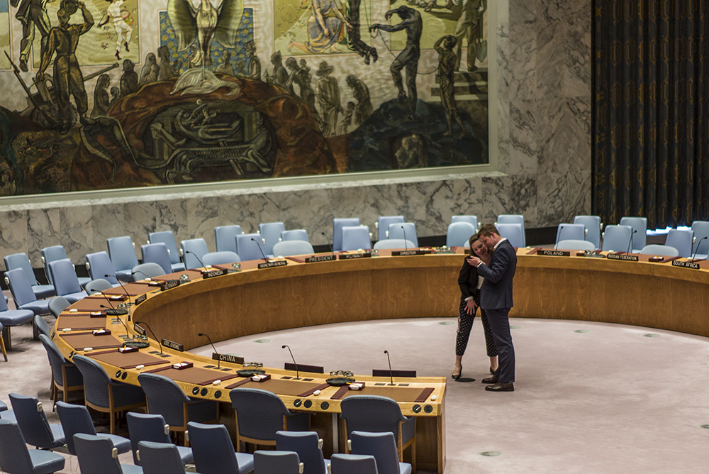 Two people looking at a phone in a debating chamber
