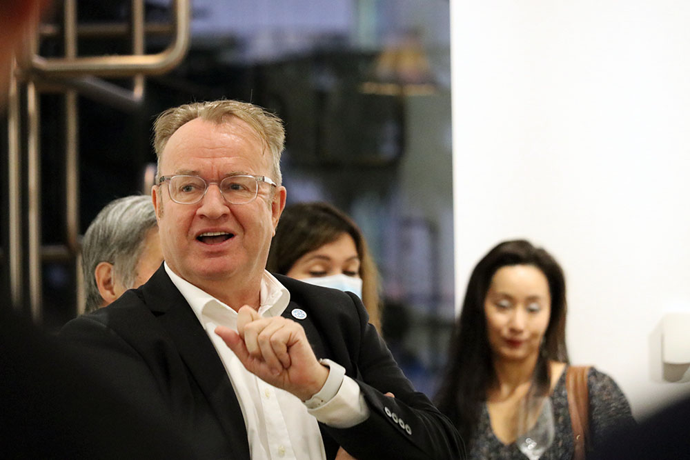 Simon gesticulating to someone at an evening event