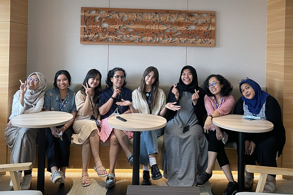 Isabella  sitting in a bench seat with seven women she works with