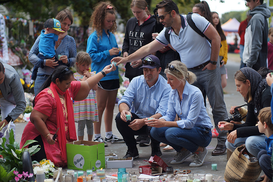 People crouching on a footpath to light candles