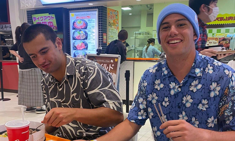 Two boys sitting at a table eating takeaways