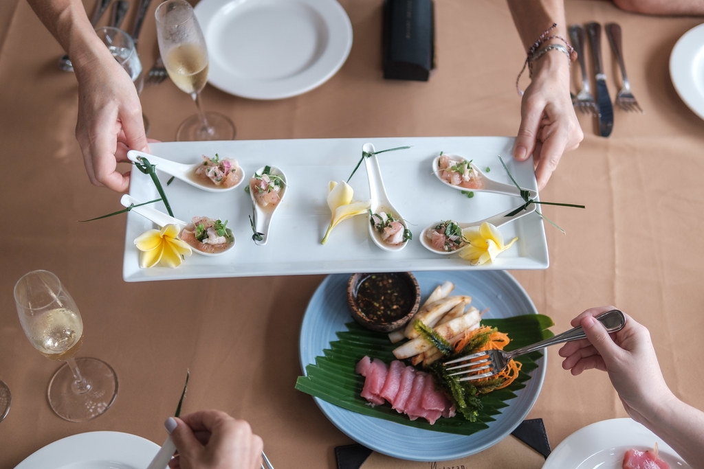 A photo of a person's hands passing a plate of Kokoda Fijian ceviche