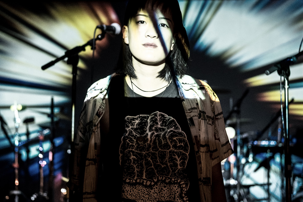 Kristen Ng standing on a stage with microphones