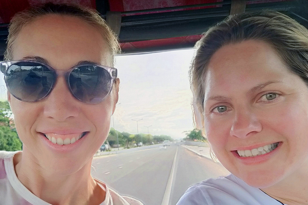 Christey and Johanna smiling at the camera from a tuk tuk