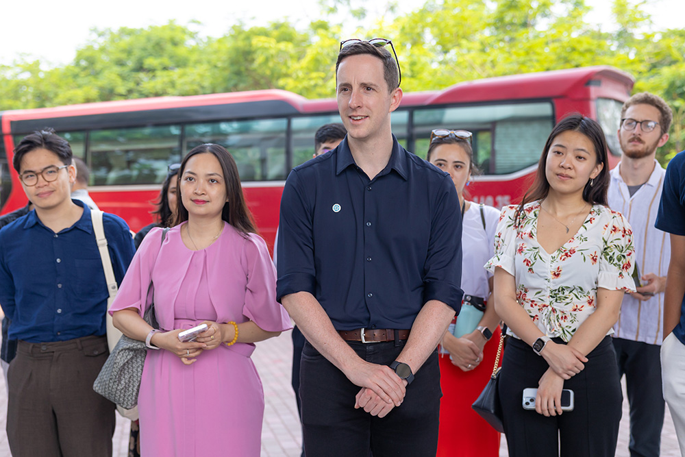 A group of Leadership Network members standing in front of a red bus. listening to someone off camera speak