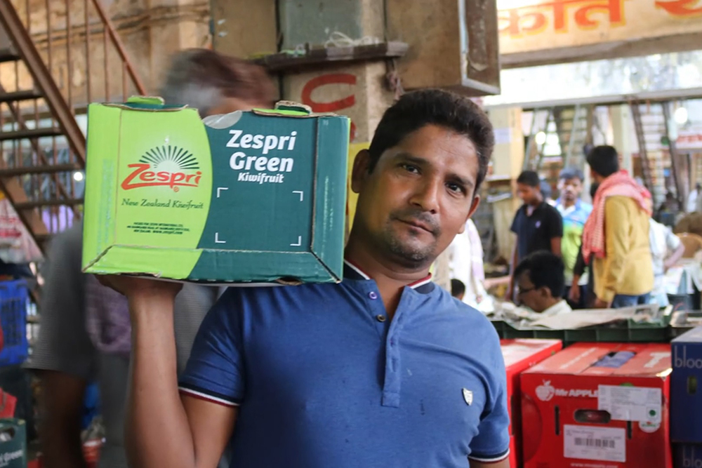 A man holding a box of kiwifruit