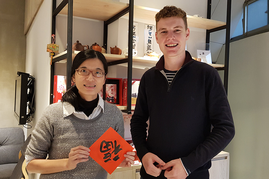 Mac Nelson standing with a colleague who is holding a piece of red paper with a Chinese character on it