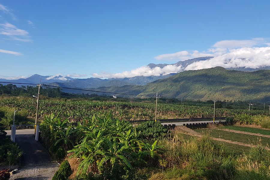 A photo of fields with cloud shrouded hills in the background
