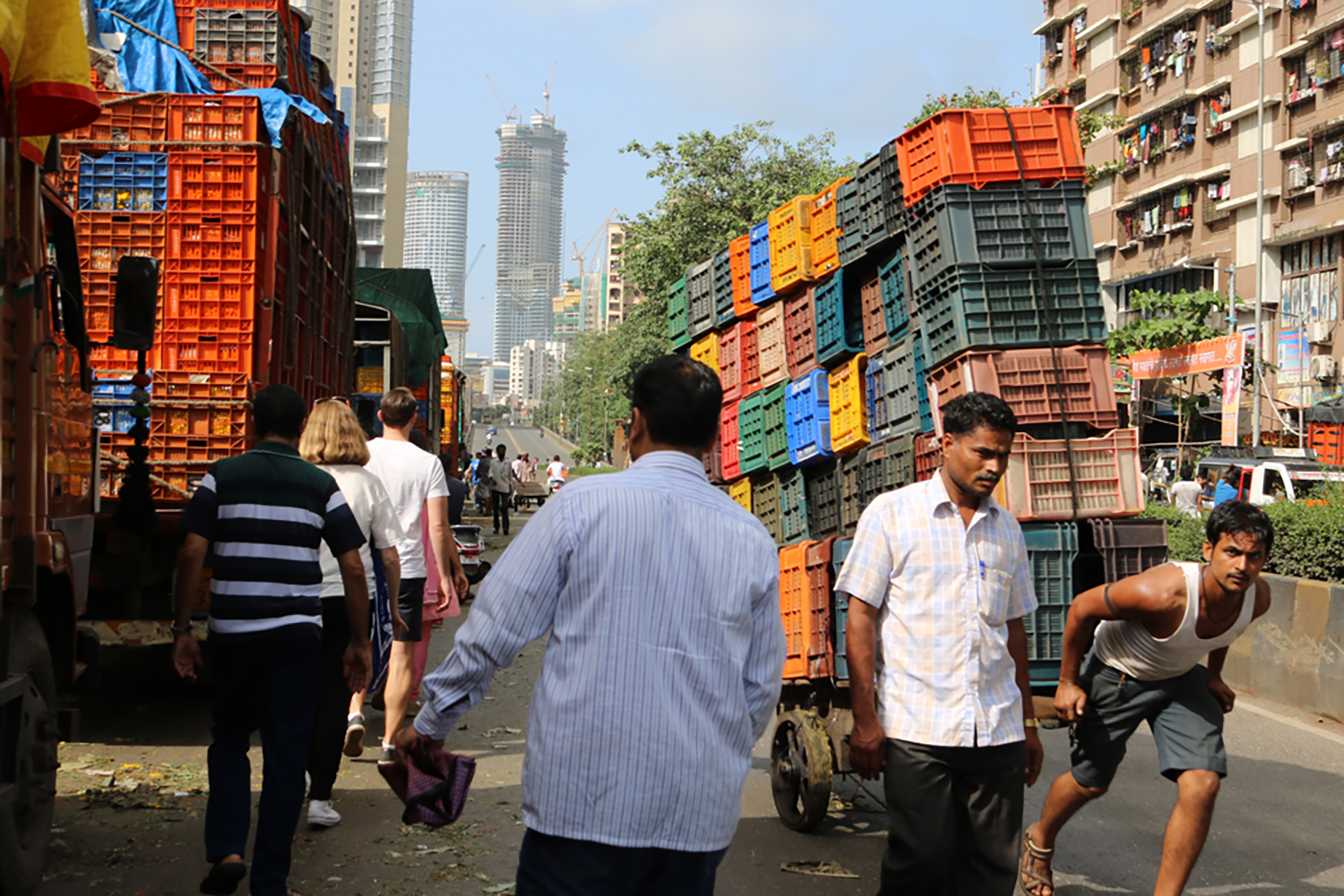 Image of a street in India - a man pulls along a cart of coloured boxes