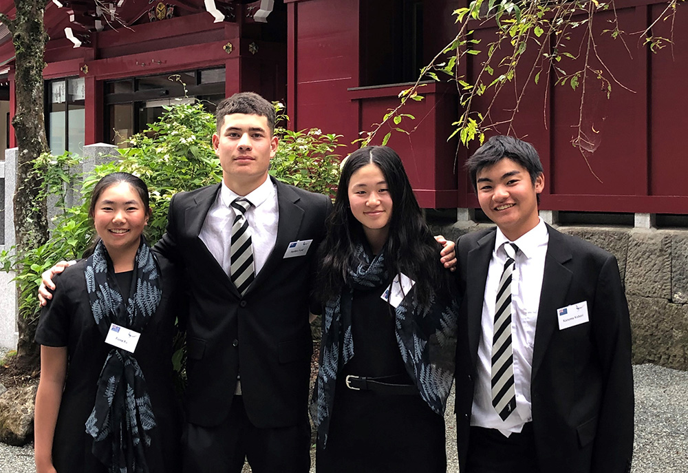 The four young golfers standing in front of a traditional Japanese building