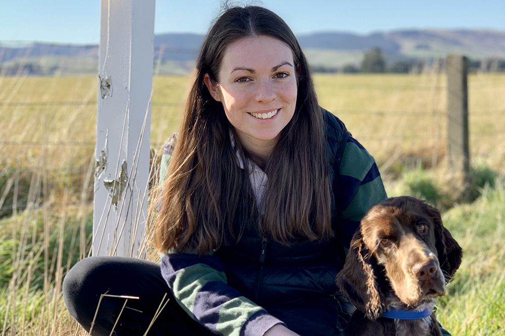 Holly sitting in a field with a dog