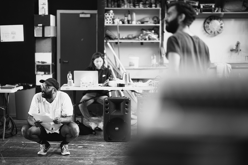 Ahi crouching on stage during a rehearsal