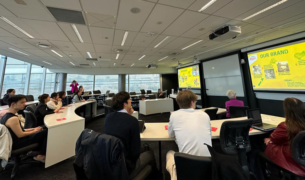 A room of people sitting at desks looking at projections on a screen