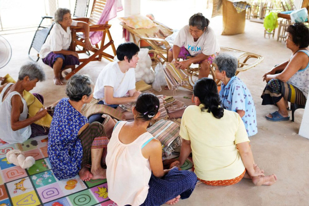 Passawee sitting on the floor talking to rural women