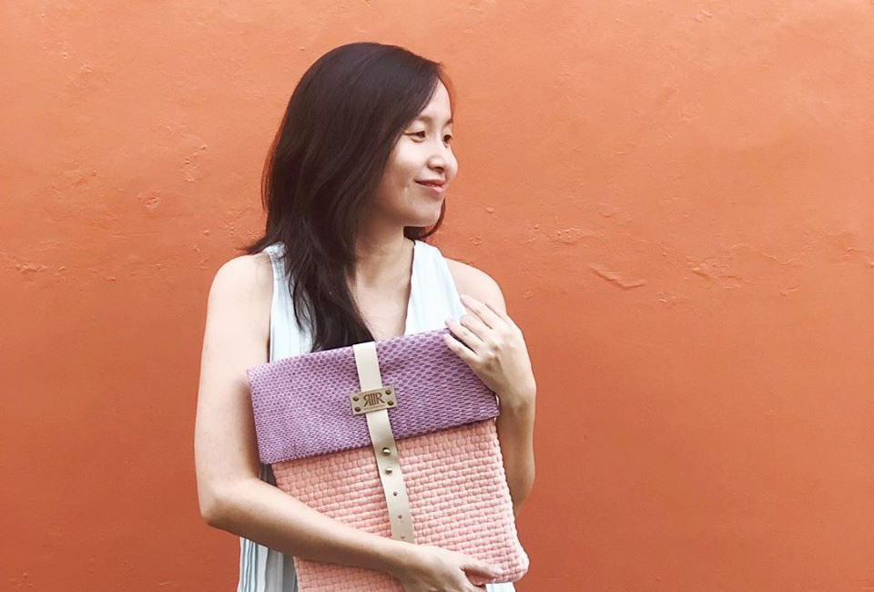 Therese holding one of Rags2Riches recycled handbags