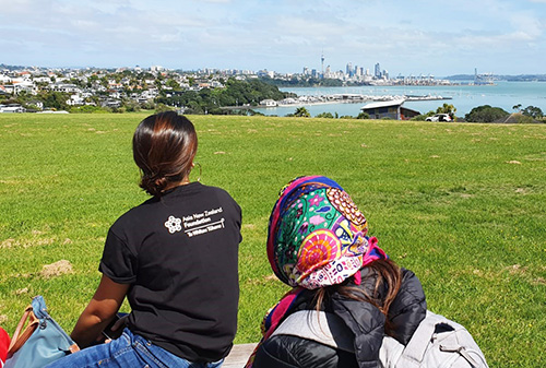Two women looking at the skyline of Auckland from a distant hill