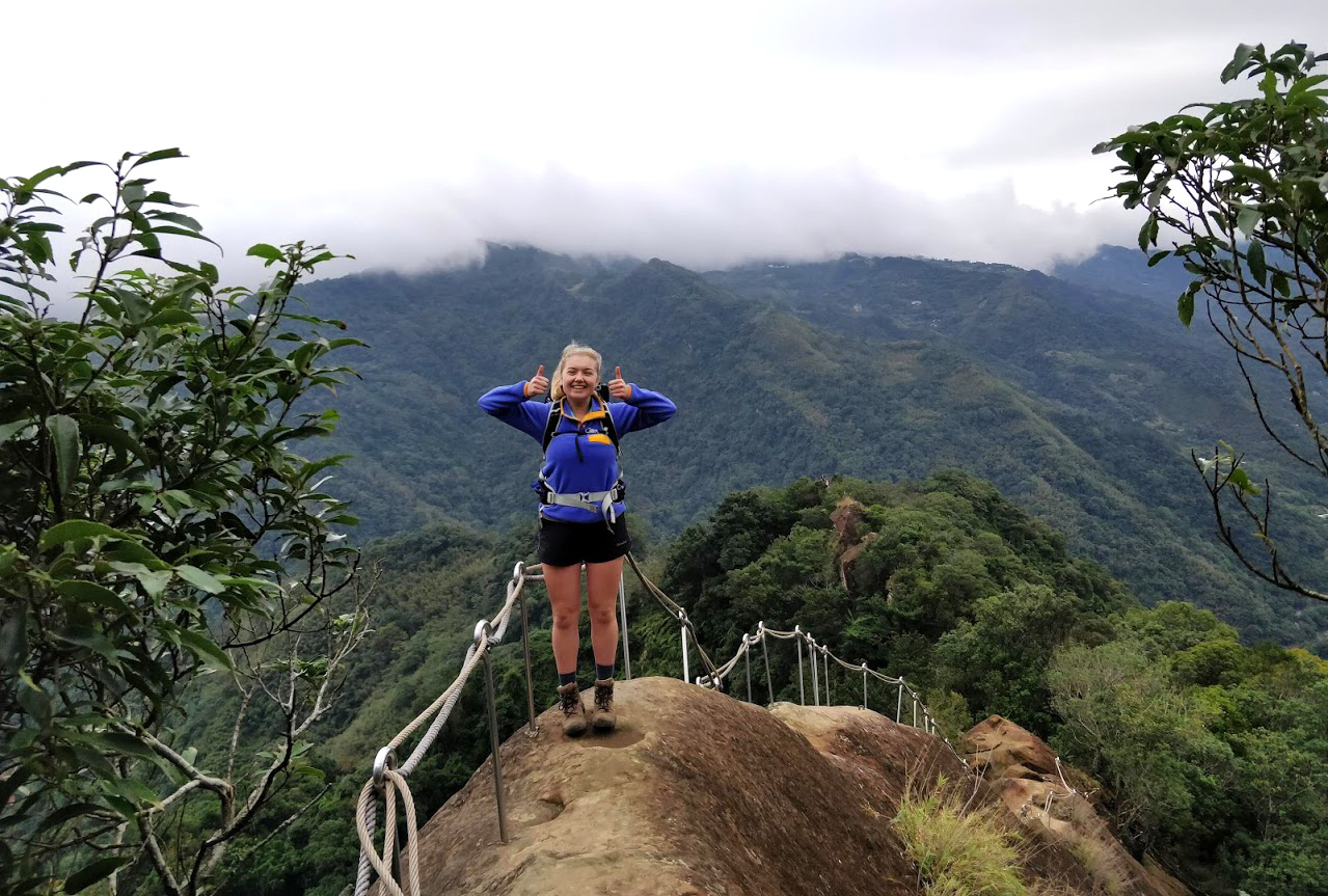 Anna standing on a rock with lush, cloud-covered mountains behind her