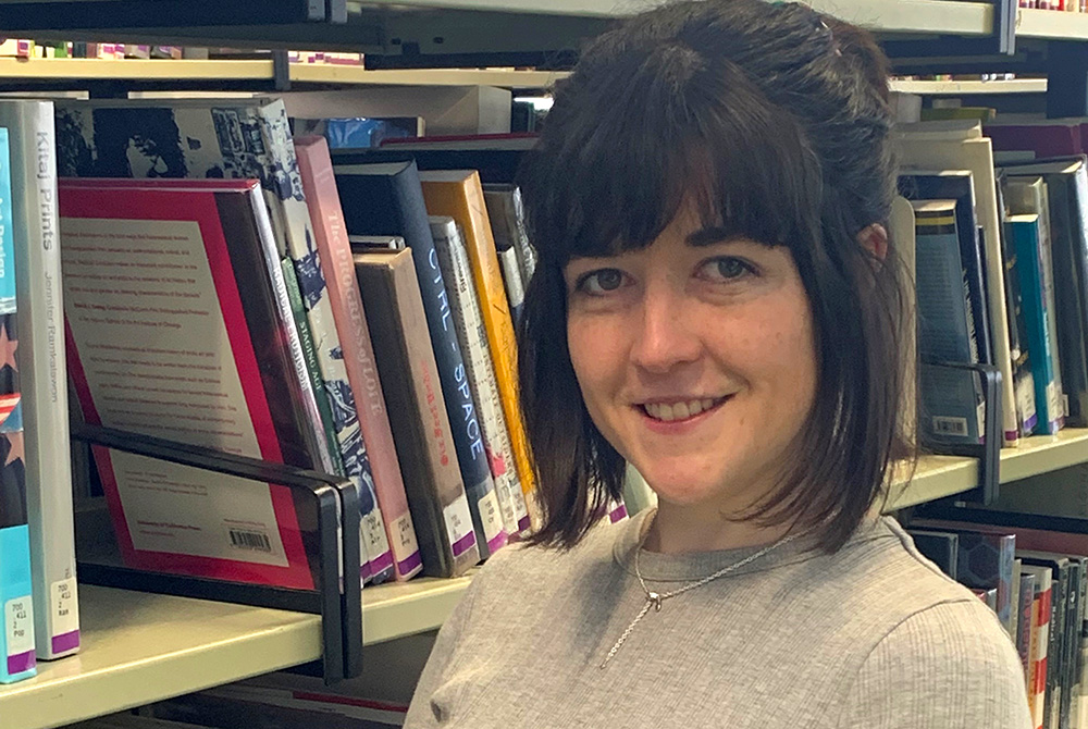 Vanessa Bramwell standing in front of shelves of library books