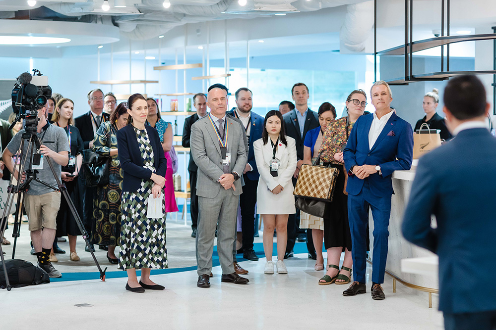 Prime Minister Ardern and the New Zealand delegation listening to a man speak